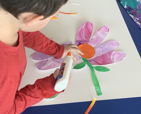 a child glues a collage of a flower