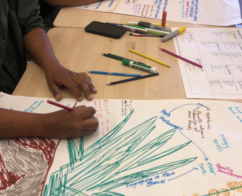 a pair of hands from two residents of the Navajo Nation use art utensils to take colorful and creative notes during a workshop